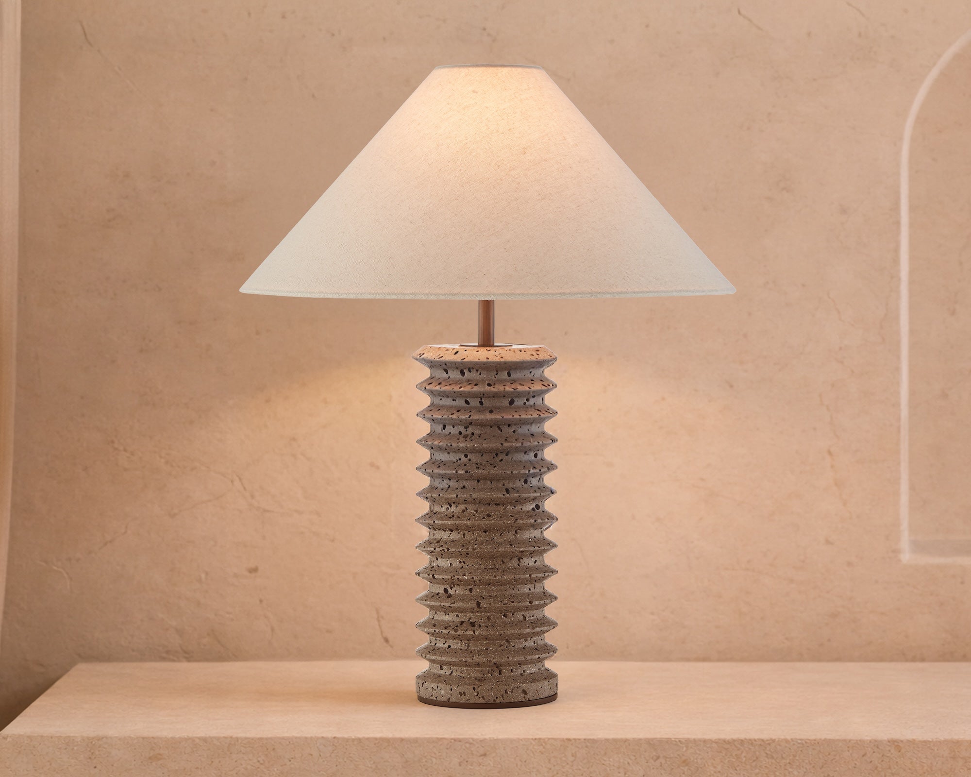Carson Table Lamp by Liang & Eimil featuring a tiered dark travertine base with antique bronze detailing and a grey linen shade