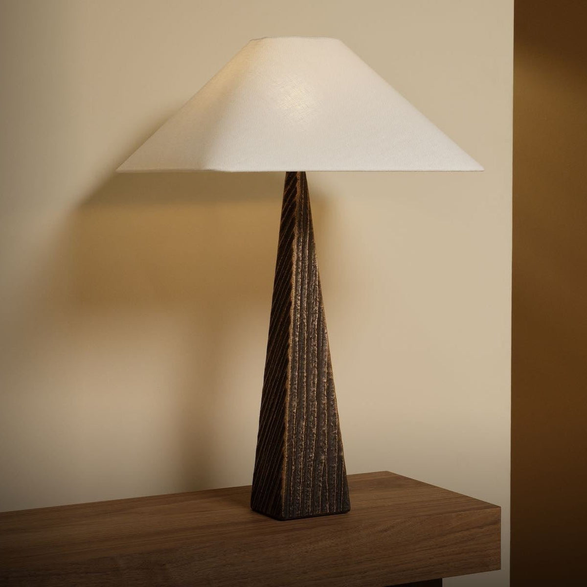 Cubist Table light showcasing its sculptural bronze base and refined linen shade