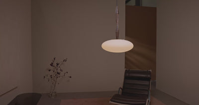 Jules Pendant 10 featuring an elongated sculptural bronze form with softly glowing opal glass